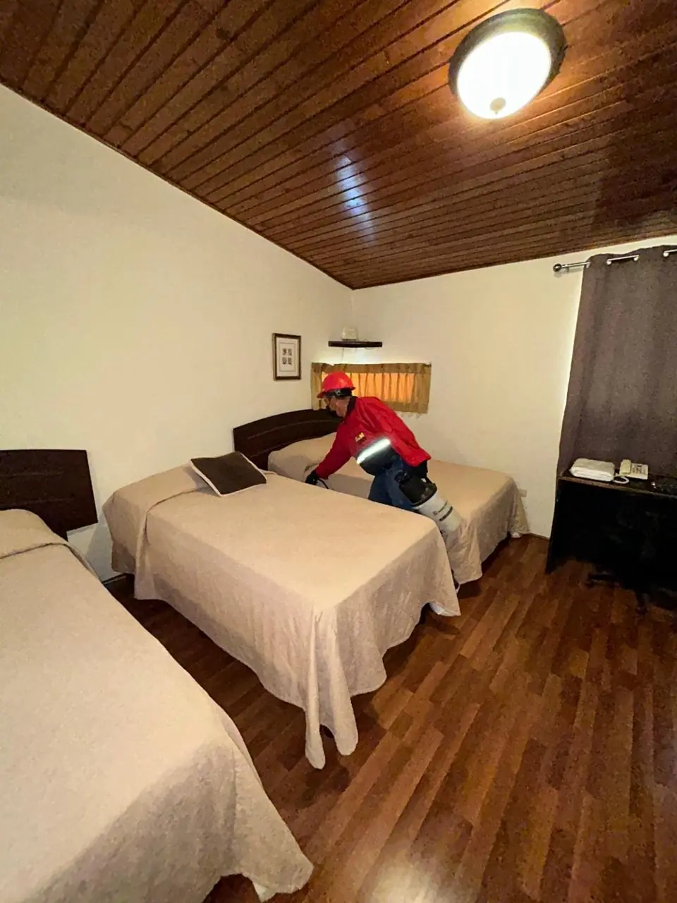 Técnico de Sin Plagas realizando control de plagas en habitación de hotel