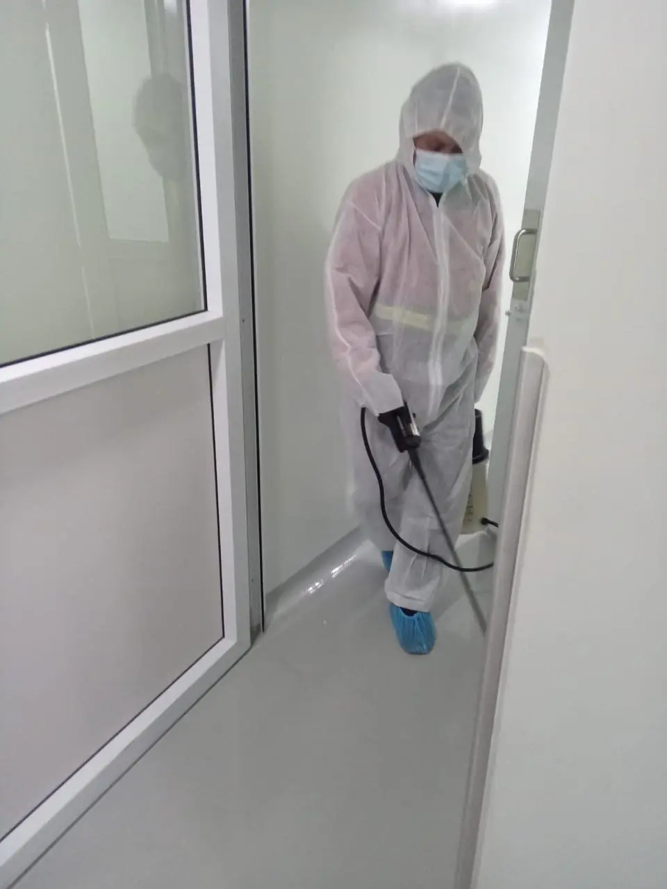 Técnico desinfectando sala limpia con equipo de protección